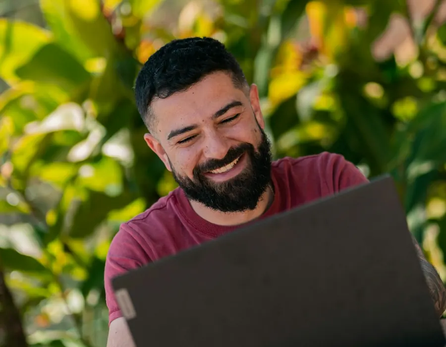 Smiling man working on his laptop surrounded by plants