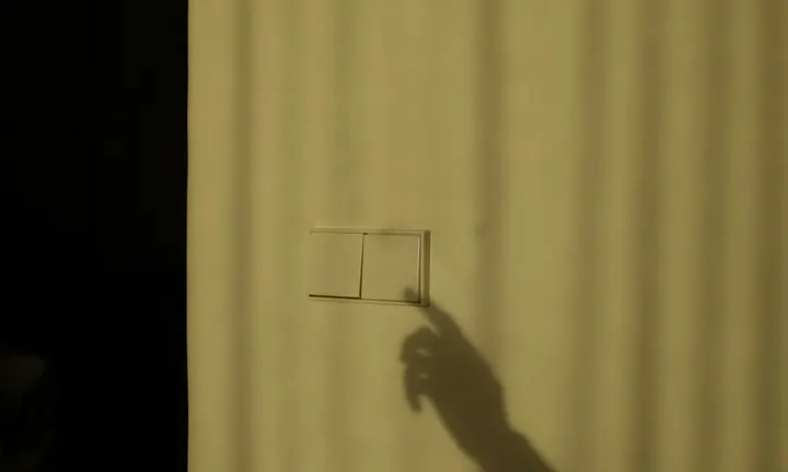 A hand reaching for a light switch